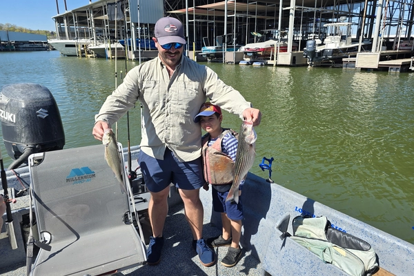Father and son holding striped bass on Lake Texoma fishing trip